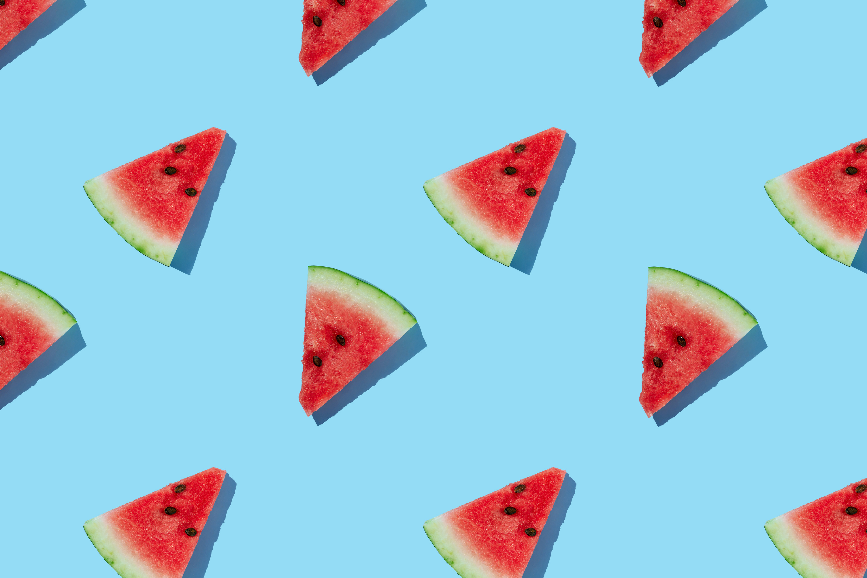 Watermelon pattern made of sliced watermelon on blue background.